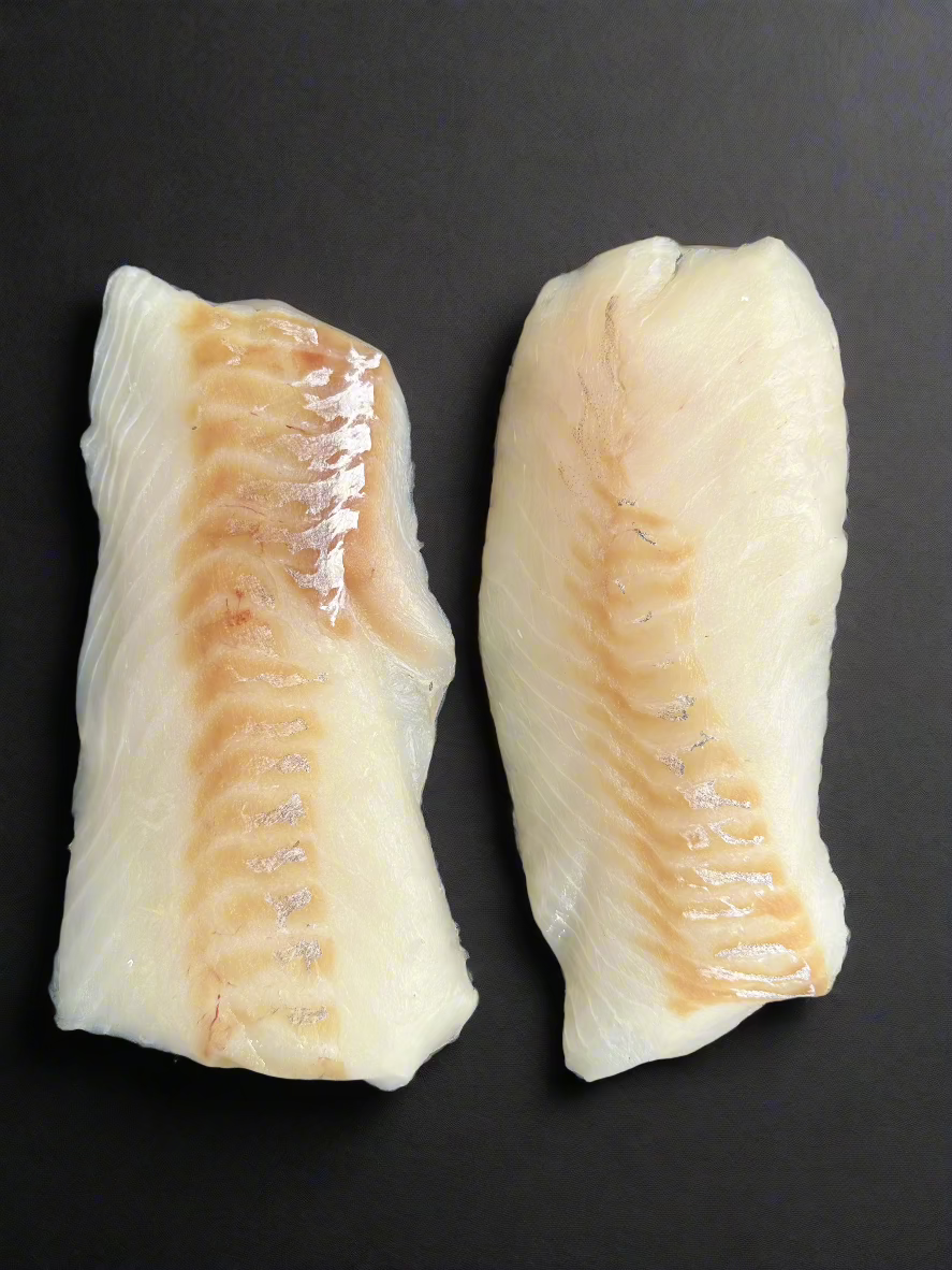Two wild-caught Alaskan halibut fillets on a dark background, showcasing their firm white texture and natural sheen. Premium, sustainable seafood from Alaska.