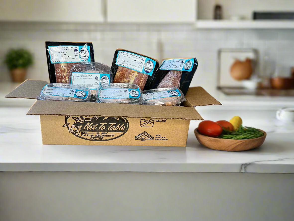Net to Table branded shipping box open on kitchen counter displaying smoked salmon portions and sockeye salmon spreads from Bristol Bay Alaska