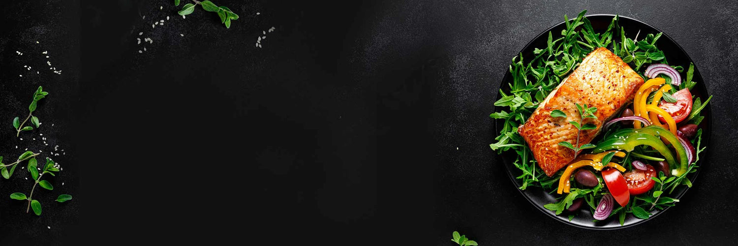 Gift Boxes - Net To Table Seafoods Grilled wild Alaskan salmon served on a black plate with a colorful salad of arugula, peppers, tomatoes, and onions on a dark textured background.