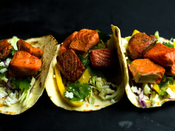 Wild-caught Alaskan salmon tacos with fresh cabbage slaw, cilantro, and peppers on corn tortillas. A vibrant, healthy seafood recipe made with sustainably sourced salmon.
