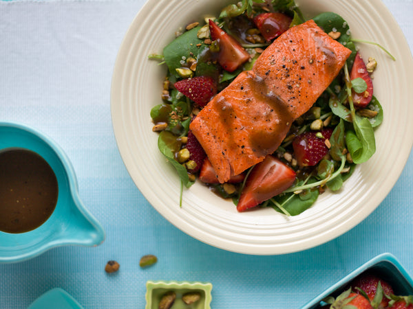 Grilled wild-caught Alaskan sockeye salmon served over a fresh strawberry and spinach salad with balsamic dressing and pistachios. A healthy, sustainable seafood meal from Net to Table Seafoods.
