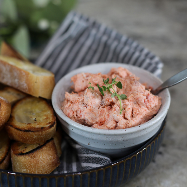 Wild Alaskan smoked salmon spread served in a rustic bowl with toasted baguette slices. Creamy, flavorful salmon dip made from sustainably caught Alaskan salmon by Net to Table Seafoods.
