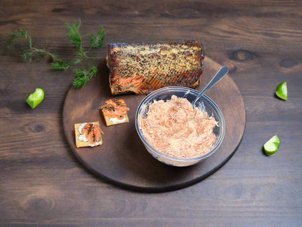 Wild-caught Alaskan smoked salmon spread served with crackers and lime on a wooden board. A rich, flavorful seafood dip made from sustainable salmon by Net to Table Seafoods.
