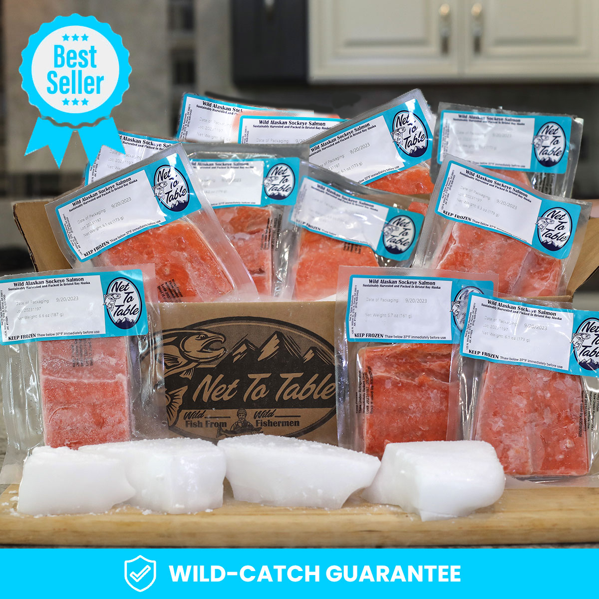 Best Seller: Box of individually vacuum-sealed wild-caught Alaskan sockeye salmon fillets from Net to Table Seafoods, displayed with ice on a kitchen counter. Features the Net to Table logo and Wild-Catch Guarantee for sustainably sourced seafood from small-boat fishermen.
