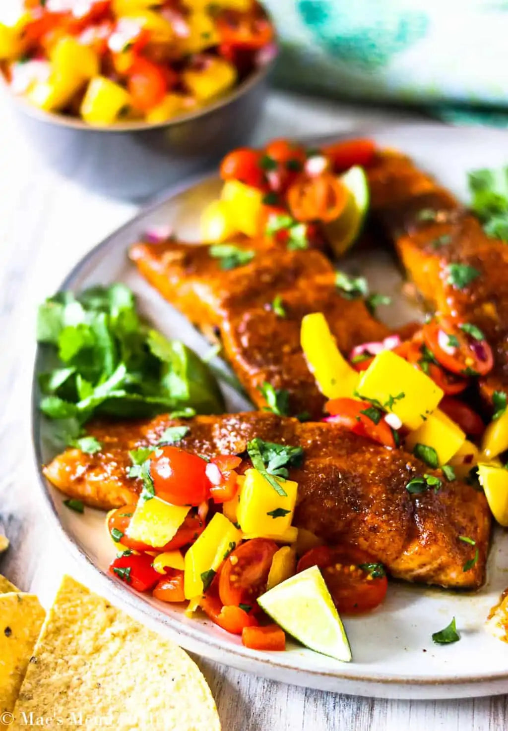 Grilled Wild Alaskan Sockeye Salmon topped with fresh mango salsa, cherry tomatoes, lime, and cilantro. Healthy wild-caught salmon recipe featuring sustainably harvested fish from Net to Table Seafoods.
