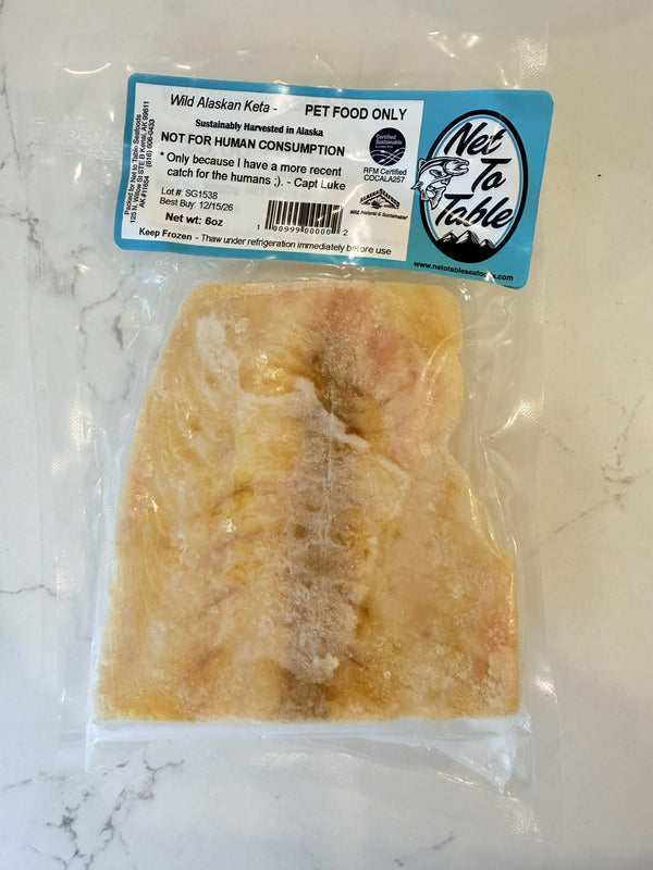 Wild Alaskan keta salmon fillet vacuum-sealed in clear packaging labeled Pet Food Only from Net to Table Seafoods on marble surface