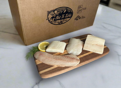 Wild Alaskan white fish variety pack with four fillets displayed on wooden board with lemon and dill, Net to Table Seafoods branded gift box